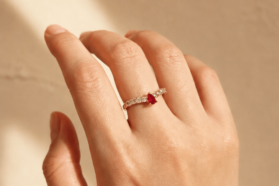 Cincin Kirana bertatah ruby dikenakan di jari manis, dalam cahaya pagi yang hangat.